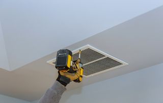 un technicien installe une VMC sur un mur