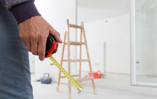 Main tenant un mètre ruban avec une échelle en arrière plan