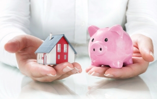 Deux mains tenant une petite maison et une tirelire cochon