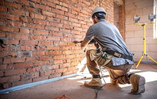 Ouvrier rénovant un mur intérieur en briques